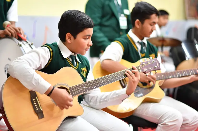 Students playing guitar in a music class at DPS Chhindwara