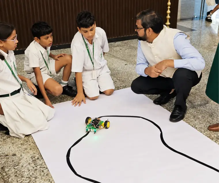 Students testing a line-following robot with their teacher at DPS Chhindwara